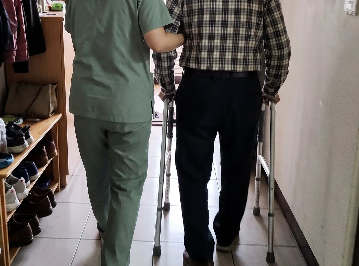阿爾瑪護理師扶著長輩在家中走廊散步 / An Alma nurse walks beside an older man down his hallway